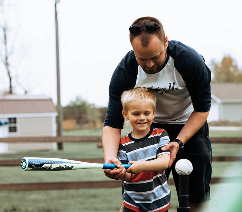Father showing his son how to hit a baseball