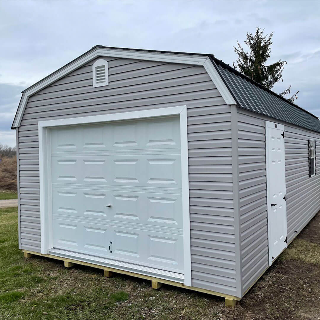 Gray gambrel garage with white trim and doors